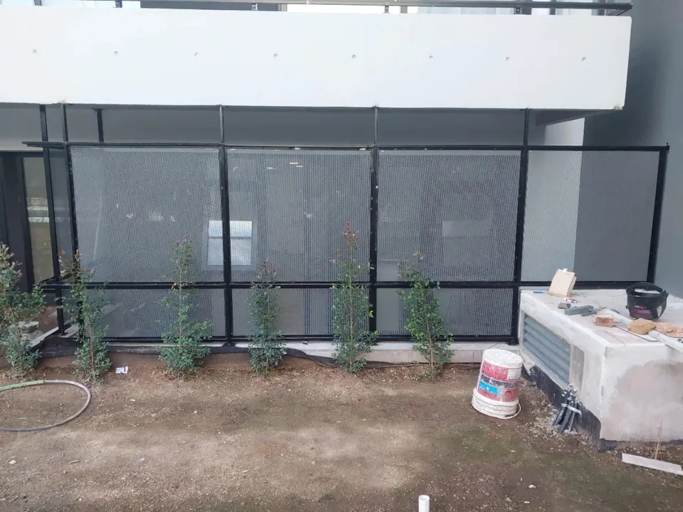 Cerramiento de metal con marco negro junto a un jardín