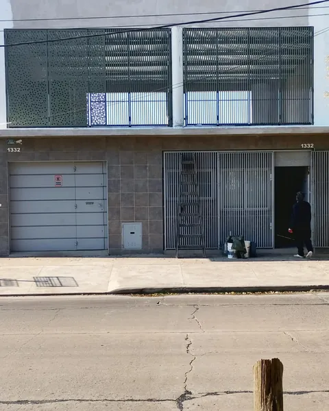 Frente de un local con portón gris y reja negra a la derecha