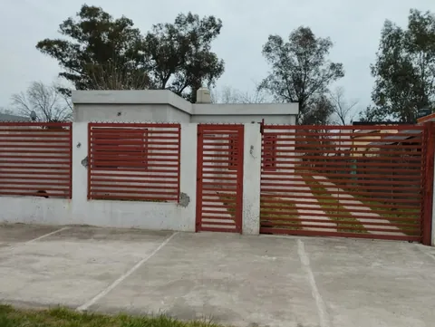 Frente de una casa con portón y puerta de hierro con listones rojos